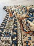 Handwoven Caucasian mountain rug with tribal protection symbols and mellowed dyes.
