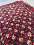 Lattice floral geometric motif Baluchi detailed close-up shot showcasing the allover repeating floral rosette design in the central field.
