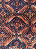 Small navy red tribal rug close-up shot of the intricate diamond lattice layout filled with small fish motifs.