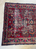 One end view of botanical theme rug with scattered wear.