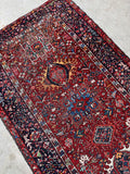 Antique Persian gallery rug. 1930s Heriz carpet with a rich crimson field, midnight blue border, and striking tribal geometric design.