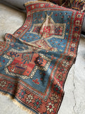 Tribal Caucasian rug with ivory-outlined central medallions.