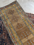 Antique Persian tribal runner featuring earthy tones, orange accents, and beautiful abrash.