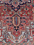 7x10 Persian Heriz rug close up featuring rectilinear tribal motifs in teal, pink, coral, green, and indigo wool.