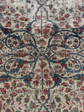 Close-up of faded botanical swirls on the ivory ground of the Persian Mahal rug.