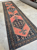 Antique Malayer runner laid out on concrete in natural light.