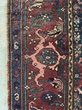 Antique Persian rug with turtle motifs woven throughout the maroon border bands.