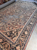 Vintage Persian Mahal rug 11x17 in mega size laid flat showing faded terracotta field and midnight blue border.