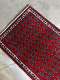 Weighted Persian rug with saturated dyes and dainty floral border.