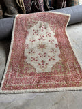 Vintage Turkish rug with an open ivory field and rich berry red and pink mauve accents.