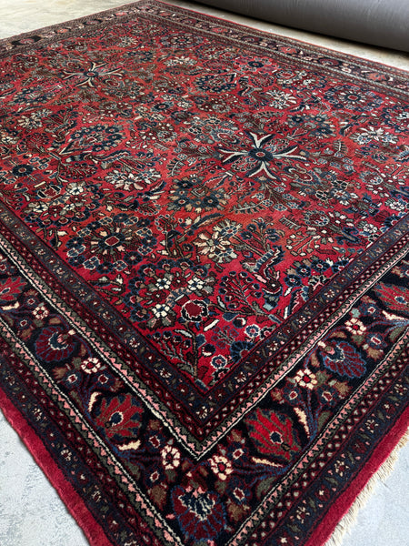 Close-up of charcoal border with ornate detailing on Persian rug.