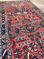 Skinny handwoven Persian rug with full floral sprays and natural dye colors.