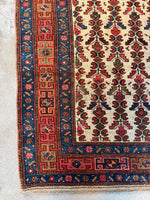 Corner view of worn Persian rug with low wool pile and abrash throughout.