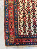 Corner view of worn Persian rug with low wool pile and abrash throughout.