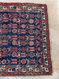 Vintage Kurdish scatter rug showing its handmade shape and worn wool surface.