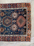 One end view of Caucasian tribal rug with secured ends and strong border pattern with abrash.