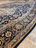 Antique Persian floral area rug from Kashan with navy blue background and ivory accents.