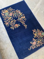 Antique Chinese rug with cascading floral pattern set diagonally in two corners.