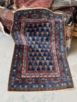 Antique Caucasian rug with navy ground and diagonal tribal stripe motifs.