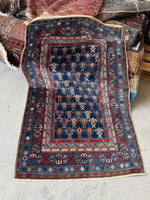 Antique Caucasian rug with navy ground and diagonal tribal stripe motifs.