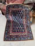 Antique Caucasian rug with navy ground and diagonal tribal stripe motifs.