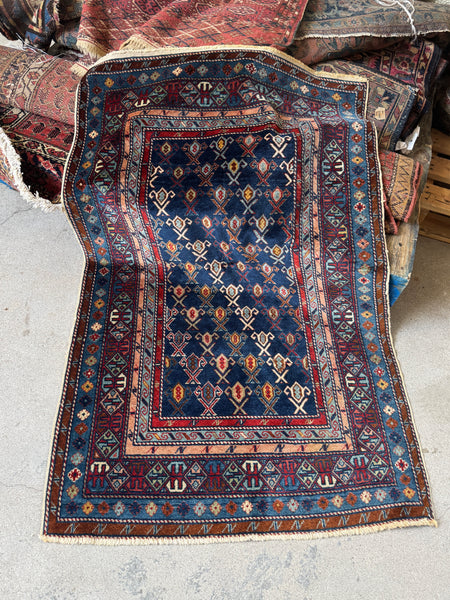 Antique Caucasian rug with navy ground and diagonal tribal stripe motifs.