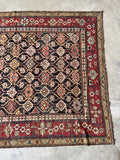 Antique Caucasian rug with charcoal field and floral border.