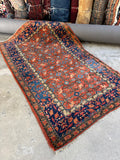 Antique Persian carpet on full display with botanical motifs and vibrant colors.