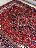 Hand-knotted antique Heriz rug with dense wool pile and bold angular floral designs.