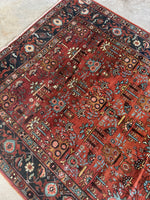Handwoven Heriz rug featuring aquamarine blue accents on a rust-toned ground.