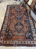 Antique Persian Shiraz rug with triple pole medallions and deep navy tribal borders.
