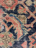 Partial view of Herati floral motifs drifting across a distressed navy background.