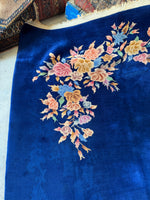Open field Art Deco Chinese rug in blue with three pastel floral bunches.