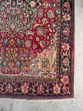 Berry red Persian area rug close-up showing French blue, soft pink, and warm ivory floral details.