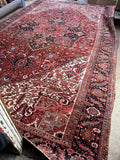 Palatial-scale antique Persian Heriz rug with saturated crimson field and ivory spandrels.
