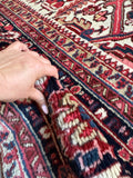 Close up of antique Heriz rug with rich navy border and colorful vegetable-dyed wool accents.