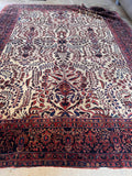 Large antique Persian floral rug shot from a high angle capturing the full room-sized proportions and rich colors.