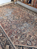 Faded terracotta vintage rug styled in a large living room showing wide room-defining scale.