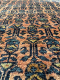 Close view of botanical border and soft floral field on a glowing Persian rug