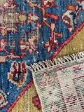 Close-up of 19th century Persian rug showing handwoven knot detail, natural dyes, and worn texture.