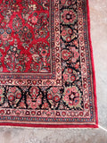 Corner view of large handwoven antique carpet highlighting exquisite floral artwork and a heavy, sturdy weave.