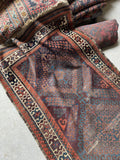 Antique Persian Baluchi skinny runner with traditional diamond pattern and low worn wool pile.