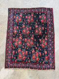 Full view of an antique Persian Bidjar rug with red floral patterns on a dark blue background.
