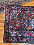 Antique Persian floral rug with ivory clover medallion and charcoal navy framing border