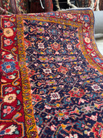 Persian scatter rug with floral chain border framing a Herati pattern.