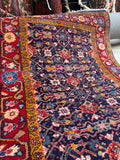 Persian scatter rug with floral chain border framing a Herati pattern.