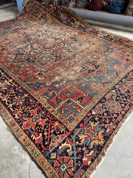 Antique Persian Heriz rug from circa 1920 with brick red ground and central medallion.