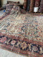 One end of large botanical rug showing scattered wear.