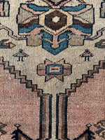Close up of Peach and blue Persian rug with bold central medallion pattern.