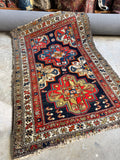 Antique 1920s Persian rug with bold geometric medallions.